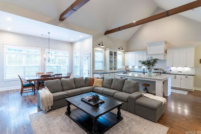 living room featuring hardwood / wood-style floors, high vaulted ceiling, an inviting chandelier, sink, and beamed ceiling