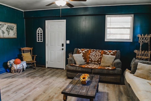 living room with ceiling fan, hardwood / wood-style floors, ornamental molding, and wooden walls