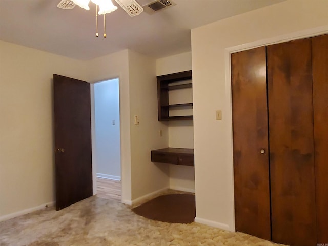 unfurnished bedroom featuring a closet, light colored carpet, and ceiling fan