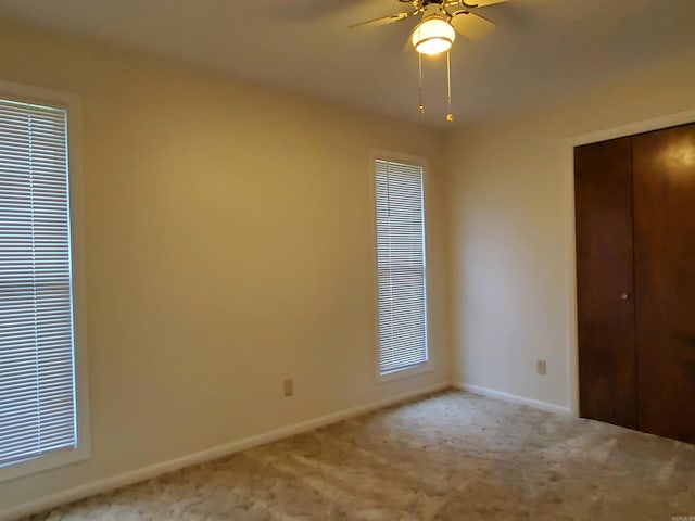 unfurnished bedroom with light carpet, a closet, and ceiling fan