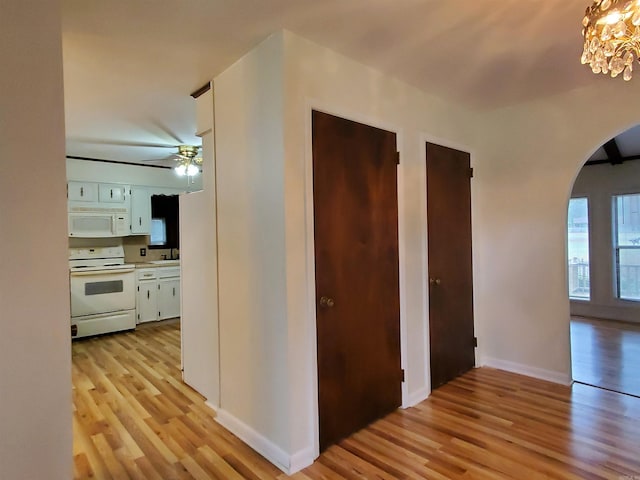 corridor with light hardwood / wood-style flooring and a notable chandelier