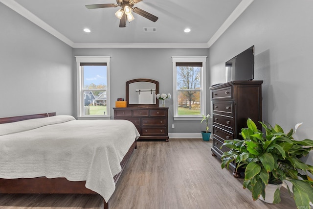 bedroom featuring wood-type flooring, ornamental molding, ceiling fan, and multiple windows