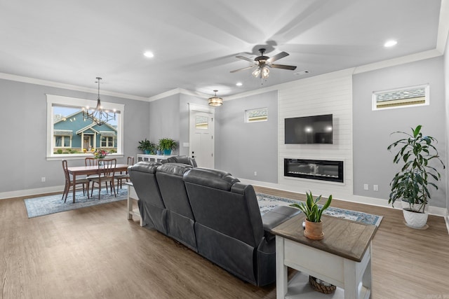 living room featuring a fireplace, ceiling fan with notable chandelier, and wood-type flooring