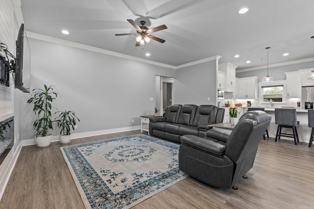 living room featuring ornamental molding, ceiling fan, hardwood / wood-style flooring, and sink