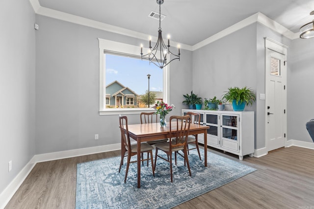 dining area featuring hardwood / wood-style floors, a chandelier, and ornamental molding