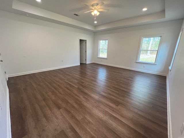 spare room featuring ceiling fan, dark wood-type flooring, and a raised ceiling