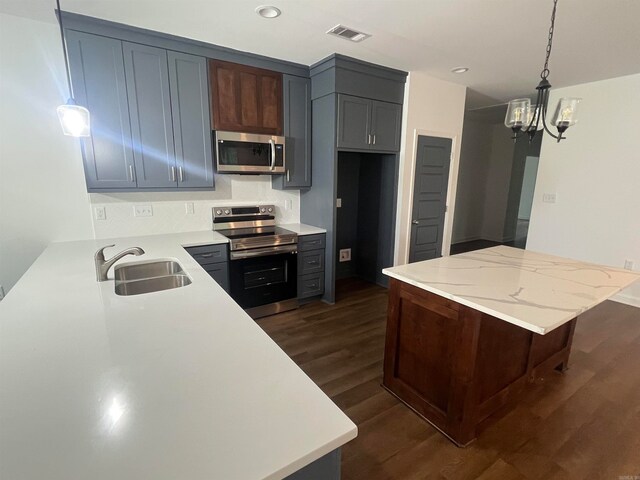 kitchen with sink, pendant lighting, appliances with stainless steel finishes, dark hardwood / wood-style flooring, and an inviting chandelier