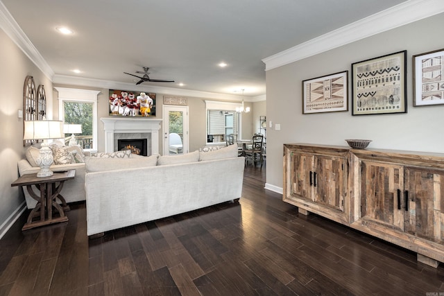 living room with ceiling fan with notable chandelier, ornamental molding, and dark wood-type flooring