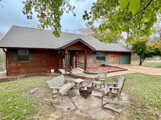 view of front facade featuring a front yard, a fire pit, a garage, and a patio area