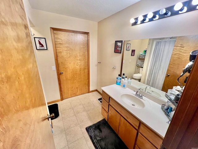 bathroom with tile patterned flooring, a textured ceiling, vanity, and toilet