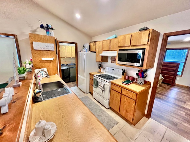 kitchen with sink, lofted ceiling, white appliances, light hardwood / wood-style floors, and washing machine and dryer