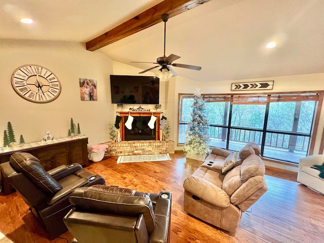 living room featuring hardwood / wood-style floors, vaulted ceiling with beams, a brick fireplace, and ceiling fan