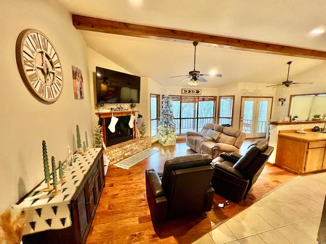 living room featuring a fireplace, vaulted ceiling with beams, light wood-type flooring, and ceiling fan