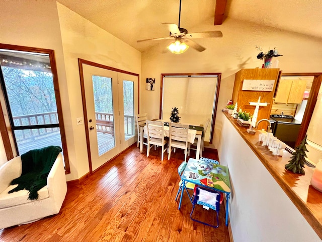 dining area featuring light wood-type flooring, a textured ceiling, lofted ceiling with beams, and ceiling fan