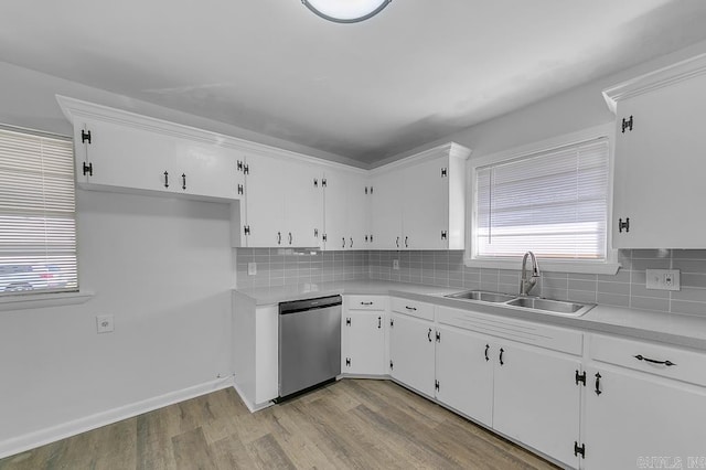 kitchen with backsplash, light wood-type flooring, stainless steel dishwasher, sink, and white cabinetry