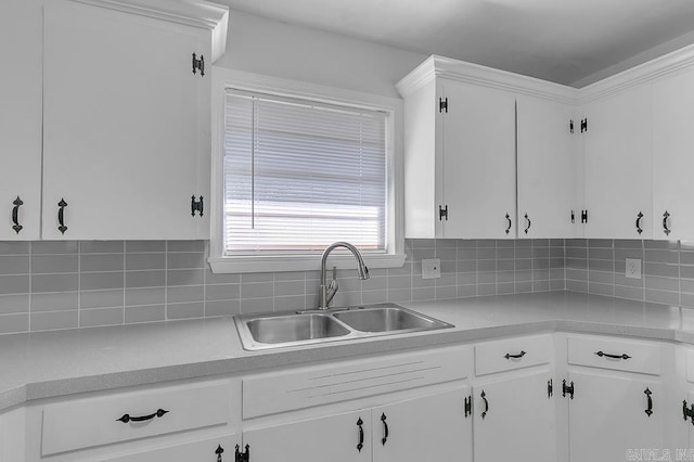 kitchen with tasteful backsplash, white cabinetry, and sink