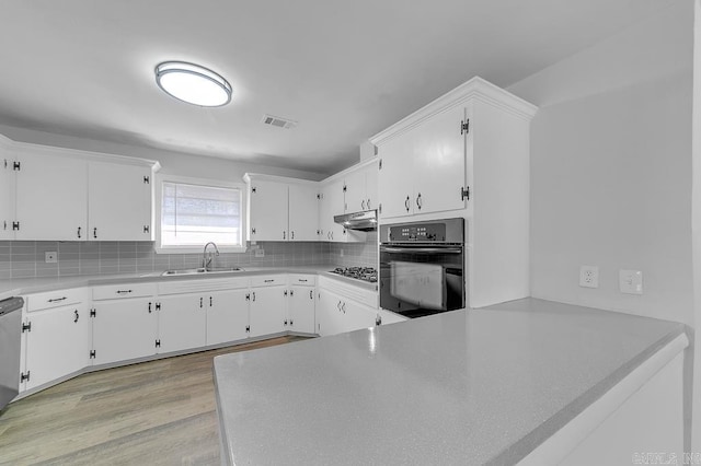 kitchen with light hardwood / wood-style flooring, white cabinetry, oven, and sink