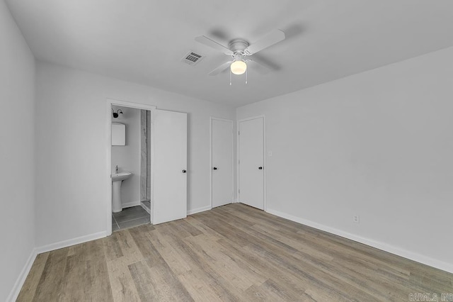 unfurnished bedroom featuring connected bathroom, ceiling fan, sink, and light hardwood / wood-style floors