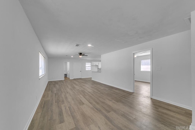 unfurnished living room featuring a wealth of natural light, ceiling fan, and light wood-type flooring