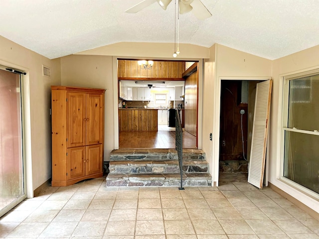 kitchen with a textured ceiling, ceiling fan with notable chandelier, and lofted ceiling