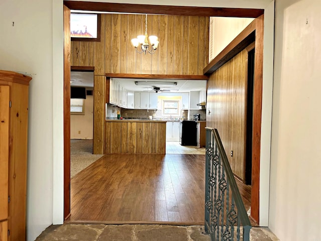 kitchen featuring light hardwood / wood-style flooring, backsplash, wood walls, black range, and white cabinets