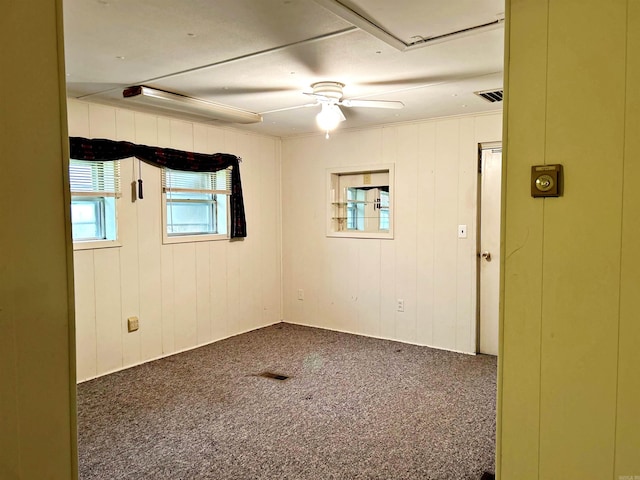 carpeted empty room featuring ceiling fan and wooden walls