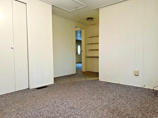 carpeted spare room featuring wooden walls