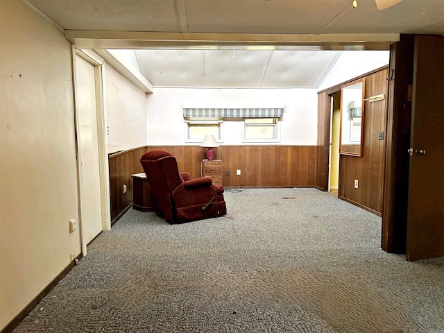 living area featuring carpet, lofted ceiling, and wood walls