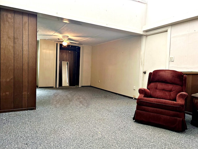 sitting room featuring light colored carpet, ceiling fan, and wood walls