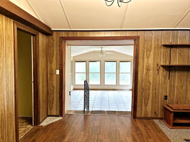 doorway to outside featuring wooden walls, dark hardwood / wood-style floors, and vaulted ceiling