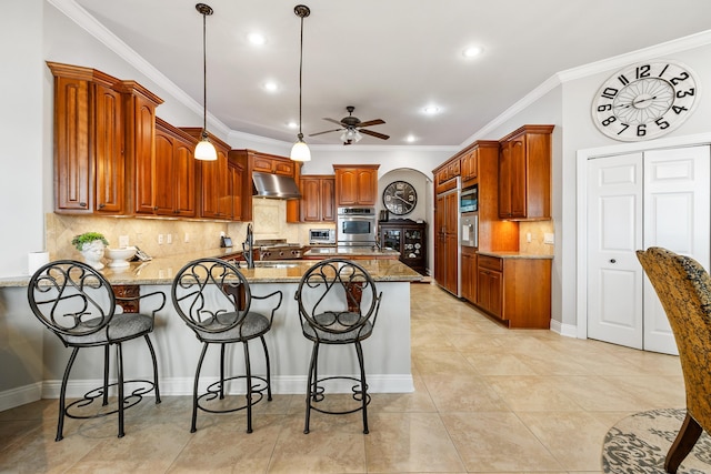 kitchen featuring ceiling fan, light stone counters, ornamental molding, and hanging light fixtures