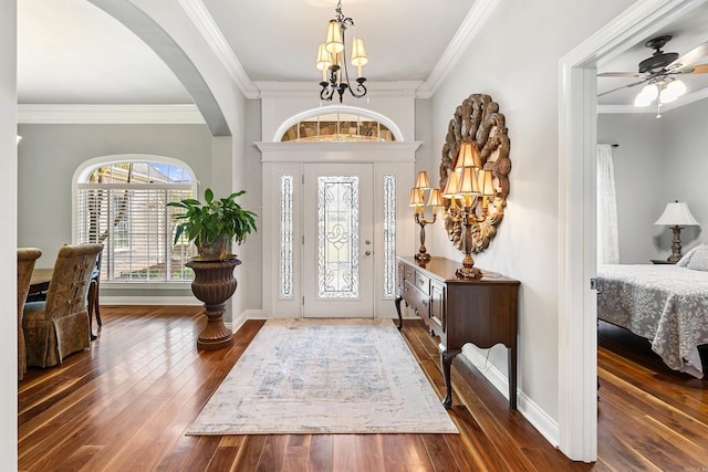 entrance foyer featuring ceiling fan with notable chandelier, dark hardwood / wood-style flooring, and crown molding