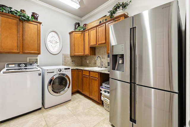 washroom with ornamental molding, sink, light tile patterned floors, and washing machine and clothes dryer