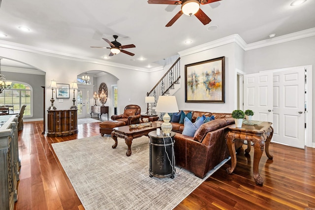 living room featuring dark wood-type flooring, ceiling fan with notable chandelier, and ornamental molding