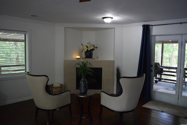 living area featuring a fireplace, ornamental molding, dark hardwood / wood-style floors, and a healthy amount of sunlight