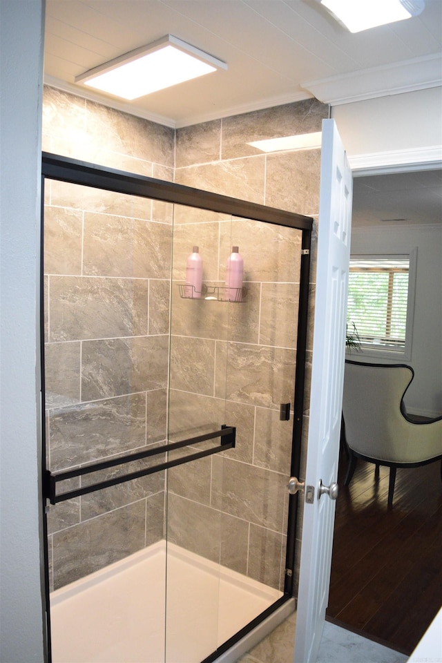 bathroom featuring hardwood / wood-style floors, a shower with shower door, and ornamental molding