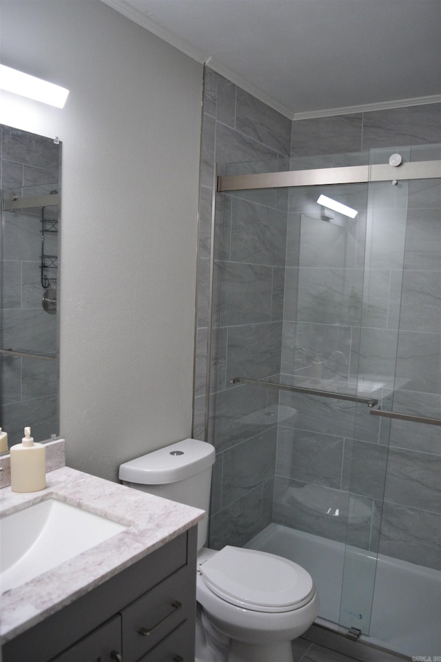 bathroom featuring toilet, vanity, a shower with shower door, and ornamental molding