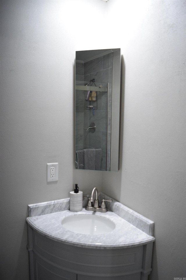 bathroom featuring a tile shower and vanity