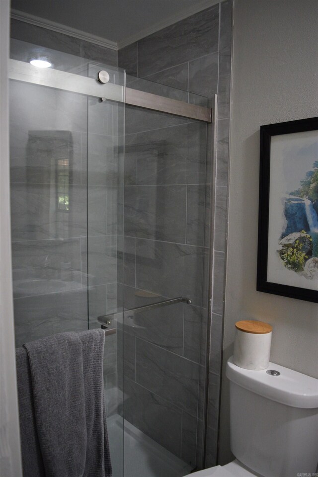 bathroom featuring toilet, crown molding, and walk in shower