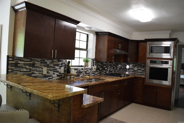 kitchen featuring kitchen peninsula, appliances with stainless steel finishes, dark brown cabinetry, and backsplash