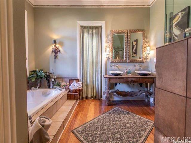 bathroom featuring vanity, ornamental molding, hardwood / wood-style flooring, and a relaxing tiled tub