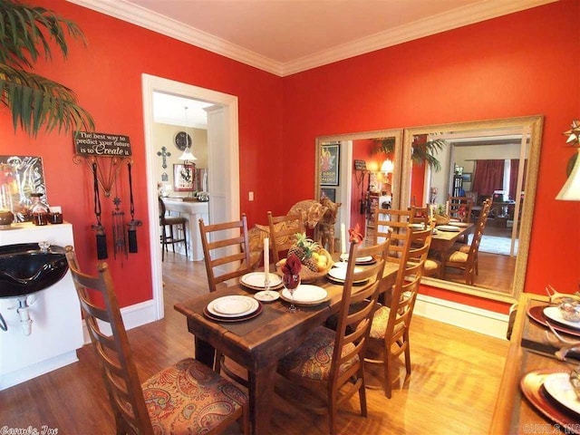 dining area with wood-type flooring, sink, and crown molding