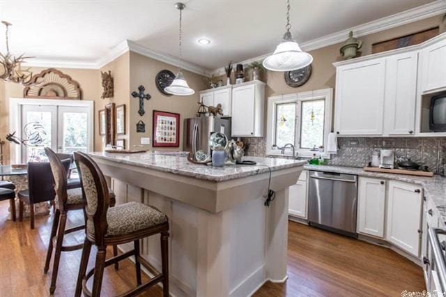 kitchen with white cabinetry, a kitchen island, stainless steel appliances, and pendant lighting