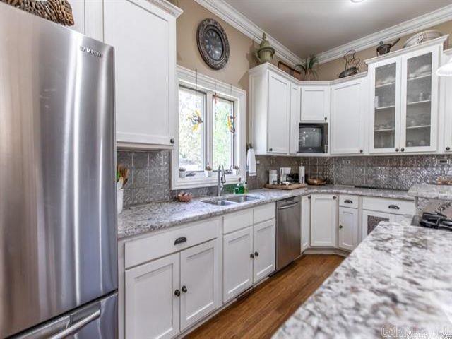 kitchen with light stone countertops, sink, stainless steel appliances, and white cabinetry