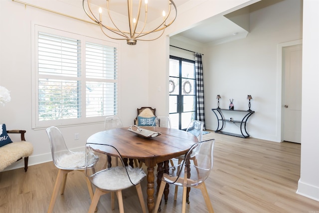 dining space with light hardwood / wood-style flooring, plenty of natural light, and a notable chandelier