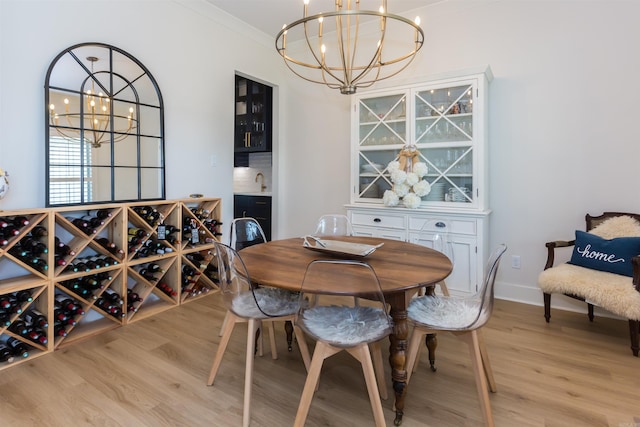 dining area with an inviting chandelier, ornamental molding, and light wood-type flooring