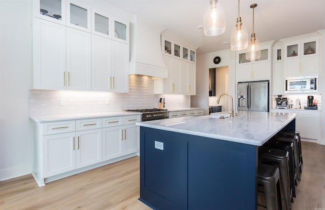 kitchen with a center island with sink, light hardwood / wood-style floors, white cabinetry, and appliances with stainless steel finishes