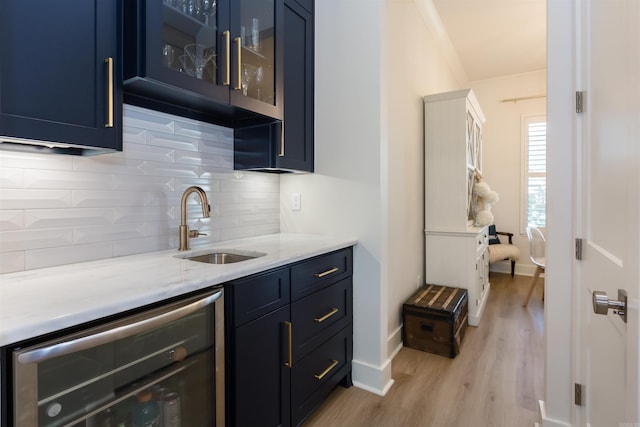 bar with sink, wine cooler, blue cabinetry, light hardwood / wood-style floors, and light stone counters