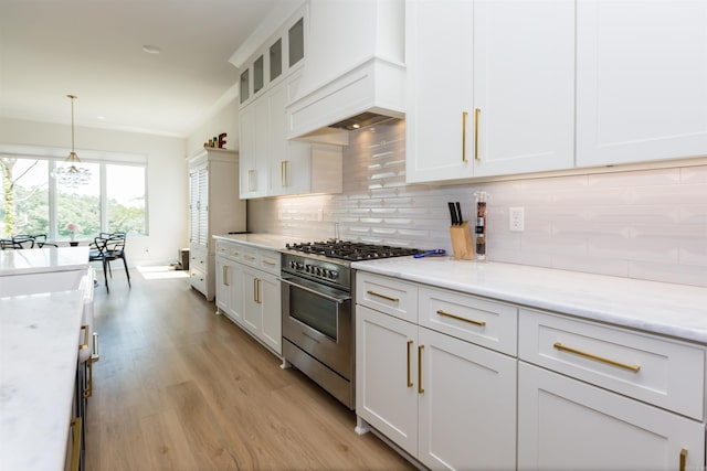 kitchen with decorative backsplash, light stone counters, custom range hood, high end stainless steel range oven, and white cabinets