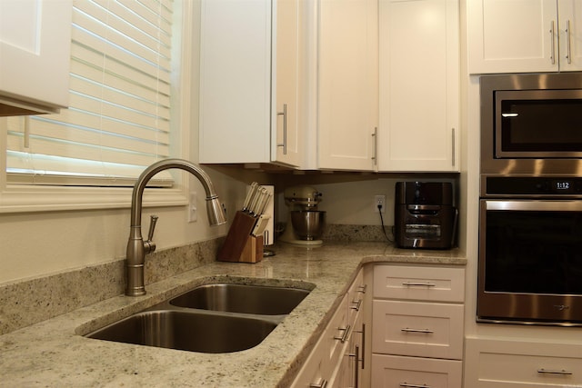 kitchen with white cabinets, light stone countertops, and sink